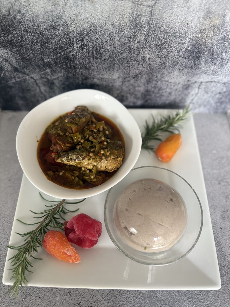 Plated NuSwan Superfood Fufu alongside a rich fish and okra stew, with colourful peppers and herbs for garnish